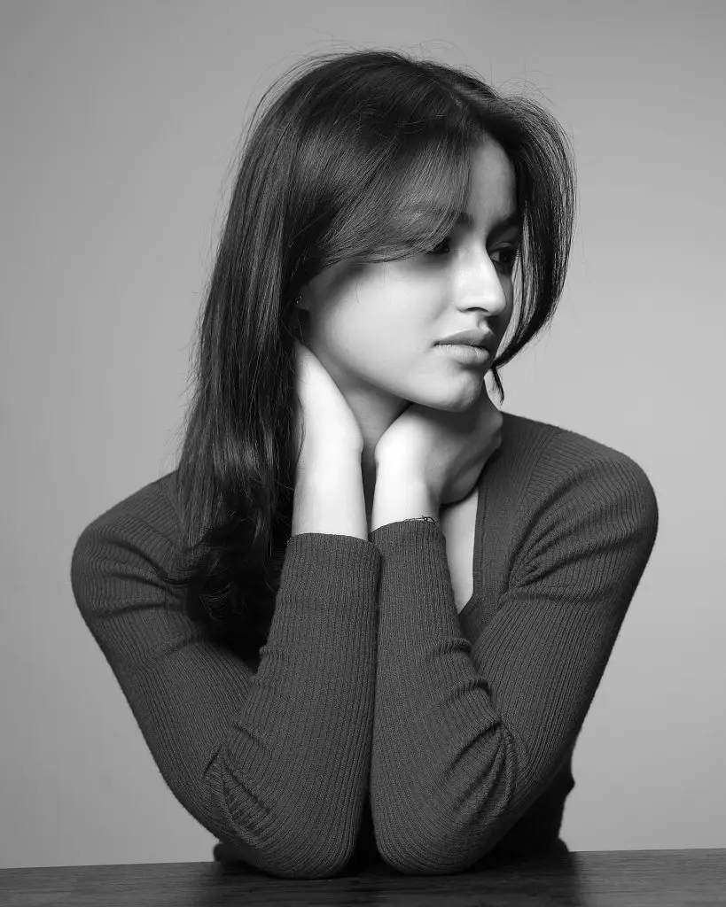 Portrait artistique d'une jeune fille. Noir et blanc, lumière douce et contrastée. Plan taille, pose assise. Attitude songeuse. Photo prise par le studio Tajan à tarbes.