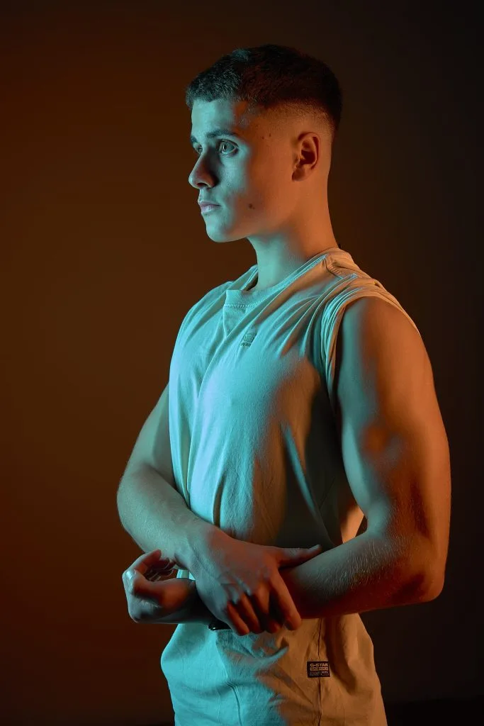 Portrait d'un jeune homme avec des lumières colorées par des gélatines. Plan taille. Réalisé par le studio Tajan à tarbes.