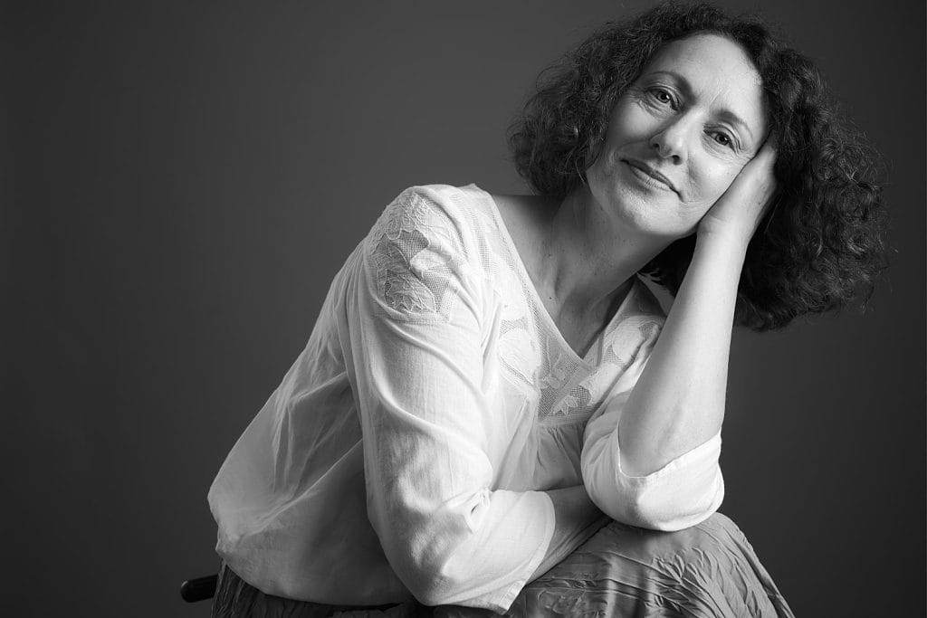 Portrait féminin en noir et blanc en studio à Tarbes, lumière douce et contrastée, pose assise, portrait réalisé par le studio TAJAN.