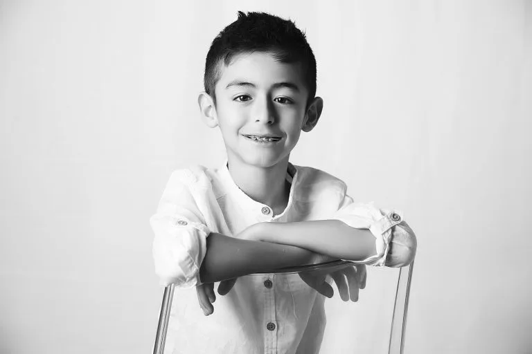 Portrait noir et blanc d'un enfant. Lumière douce et contrastée. Pose assise.