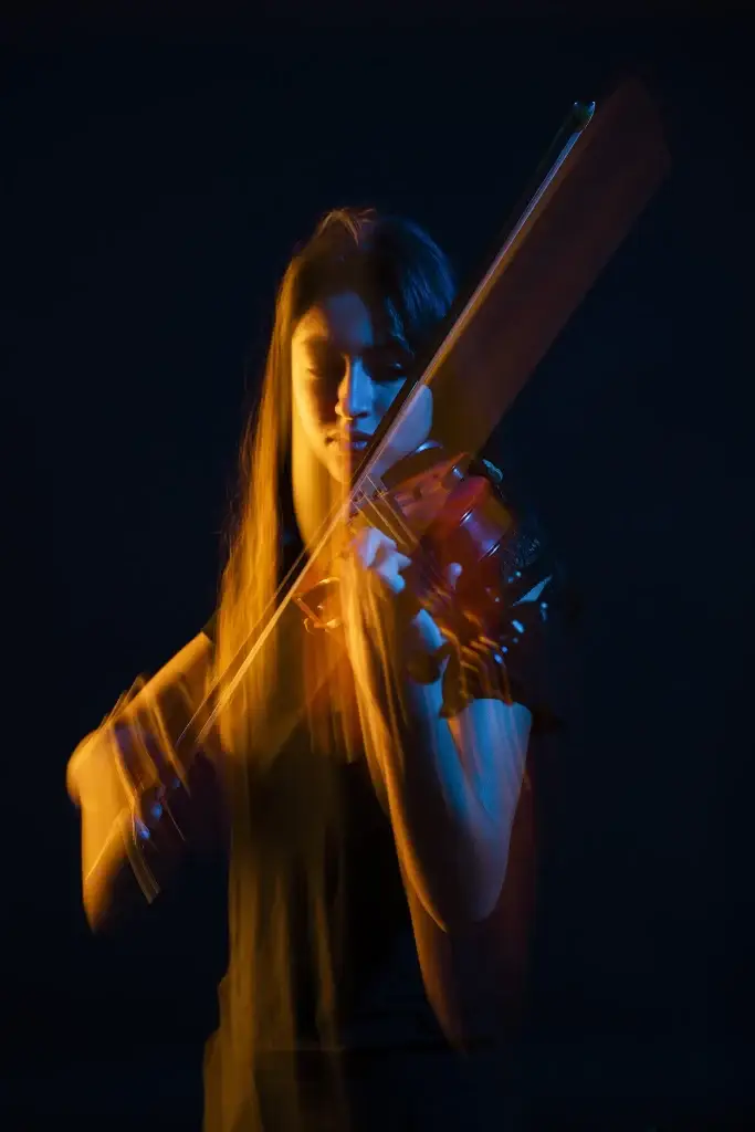 Portrait en couleur d'une jeune femme avec son violon. Utilisation de gélatines colorées pour créer un effet créatif. Dominante de bleu et d'orange. Portrait Taille. Effets de mouvements artistiques.