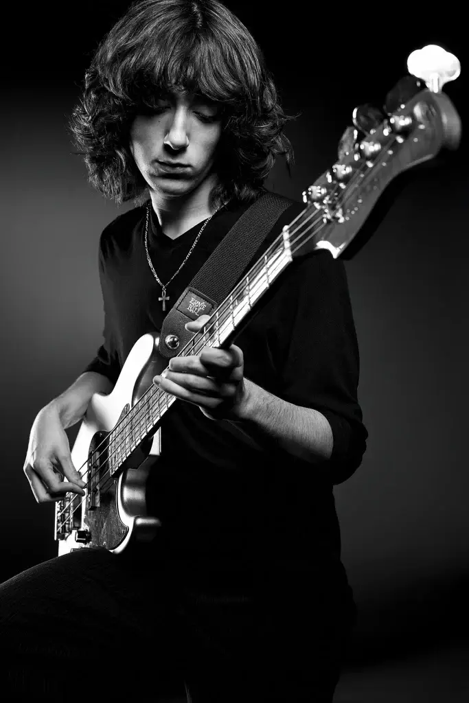 Portrait en gros plan d'un bassiste. Utilisation du noir et blanc pour créer une ambiance sombre et donner du caractère à la musique rock.