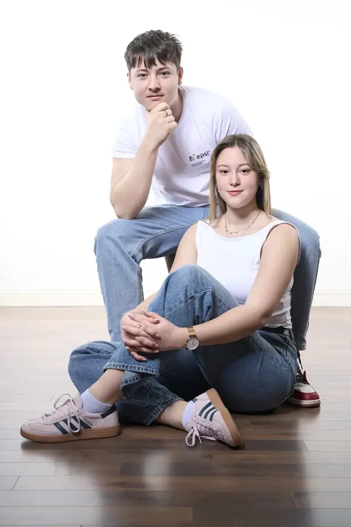 portrait couleur frère soeur réalisé sur Tarbes. La jeune femme est assise au sol tandis que le jeune homme est assis sur un tabouret. Ambiance claire et pose dynamique.