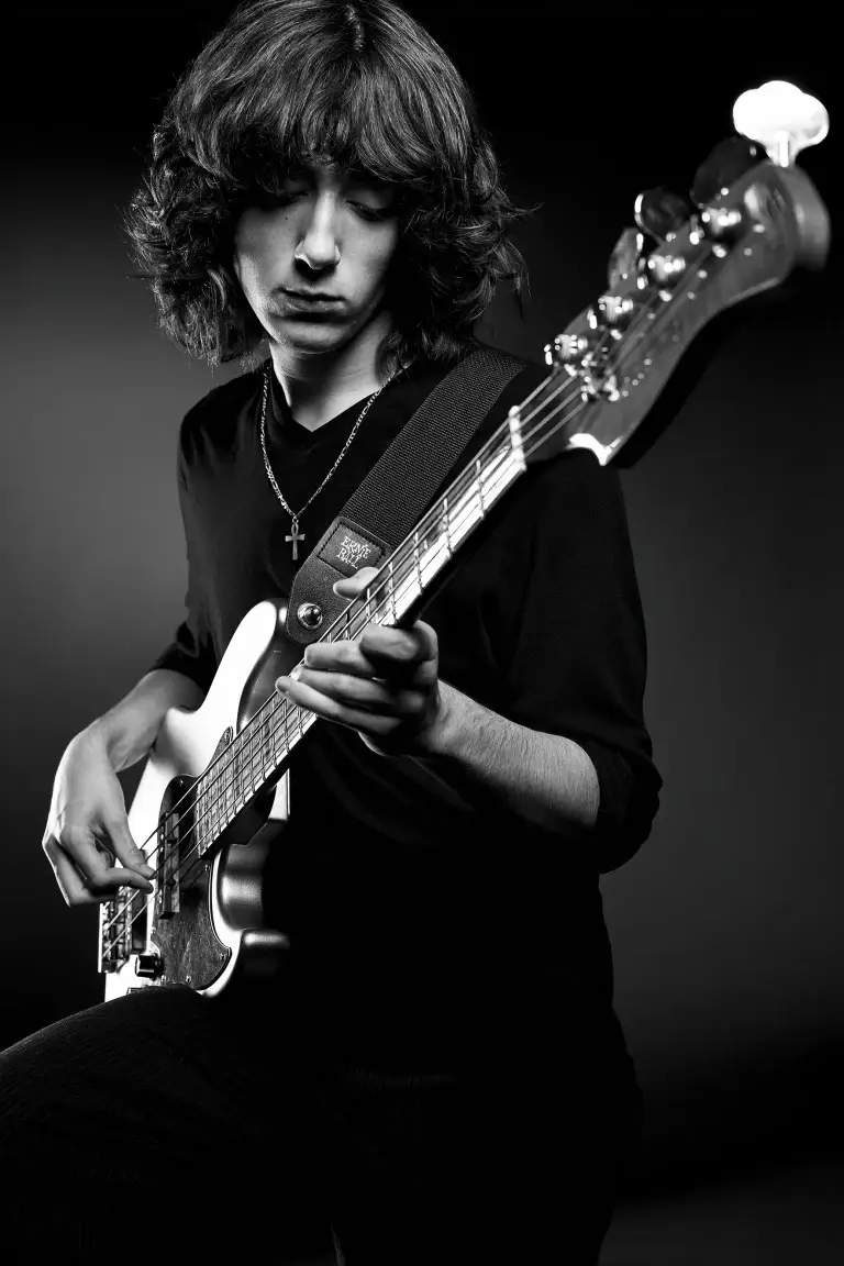 photo d'un musicien en noir et blanc. Jeune homme jouant de la basse dans une ambiance générale sombre.