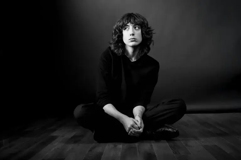 portrait d'un artiste en noir et blanc. Ambiance sombre, seuls le visage et les mains ressortent de la composition élaborée par le studio Tajan à tarbes.