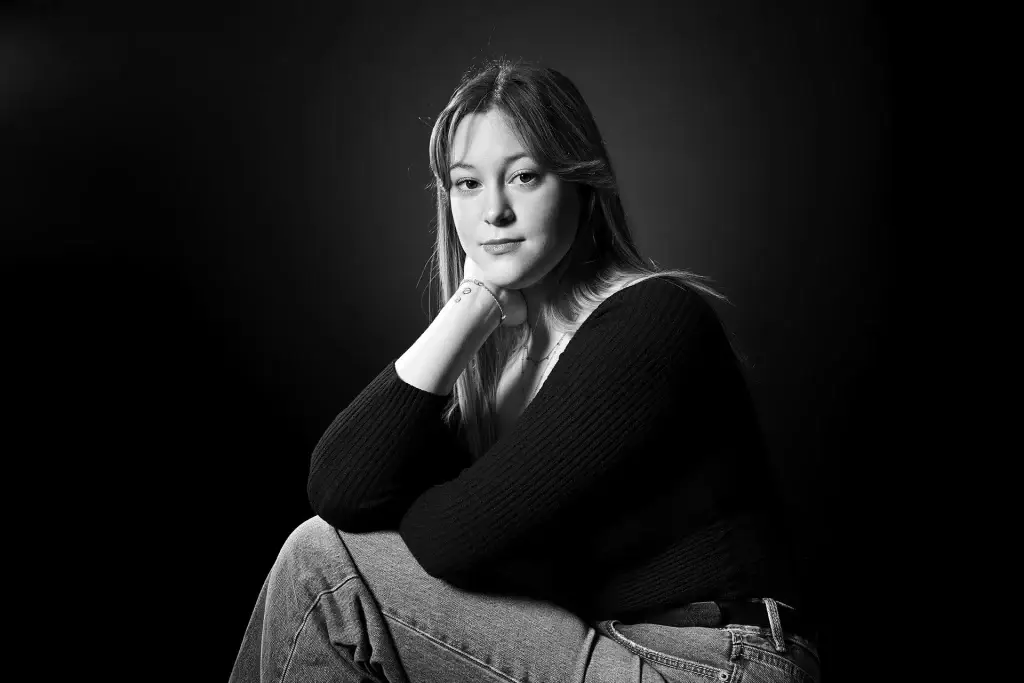 Portrait d'une jeune femme blonde assise. Le choix du noir et blanc fait par le studio tajan met bien en valeur le caractère du modele.