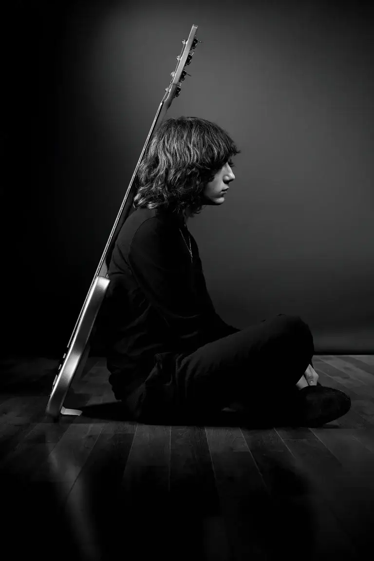 Portrait stylisé d'un bassiste en noir et blanc. Celui ci est accroupi, sa basse posée sur son dos. L'ensemble constitue un triangle. Photo prise par le studio tajan à tarbes.