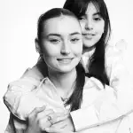 Photographie de deux soeurs en noir et blanc prise par le studio Tajan à Tarbes. La petite soeur prend dans ses bras sa grande soeur.