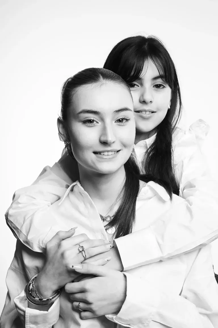 Photographie de deux soeurs en noir et blanc prise par le studio Tajan à Tarbes. La petite soeur prend dans ses bras sa grande soeur.