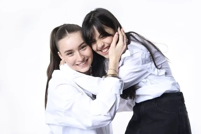Portrait joyeux de deux soeurs se tenant dans les bras en riant. Photo couleur, lumière douce et ambiance très lumineuse.