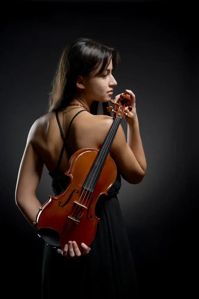 Portrait original en couleur d'une violoniste tenant son violon dans le dos.