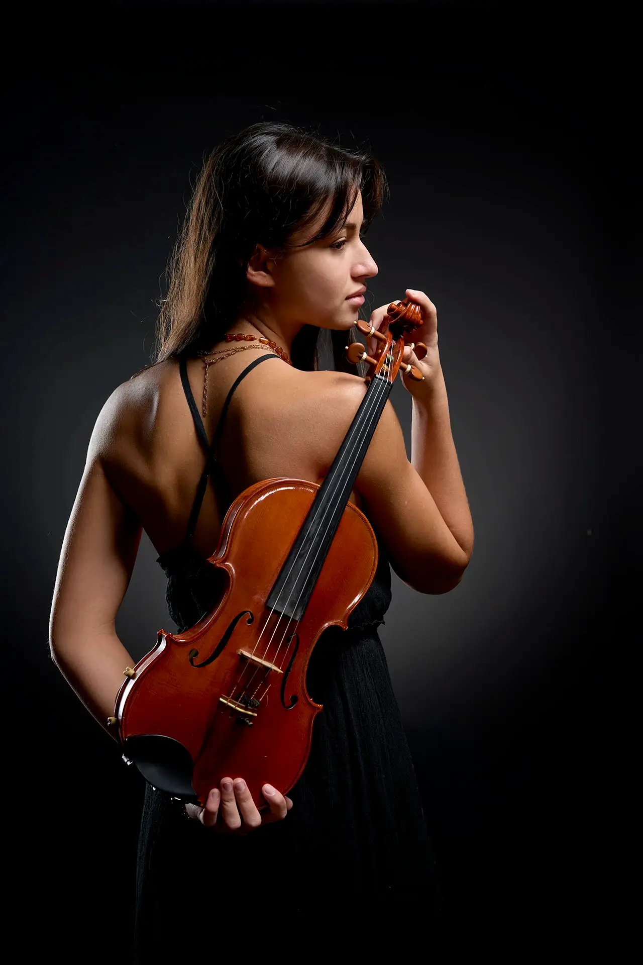 Portrait original en couleur d'une violoniste tenant son violon dans le dos.