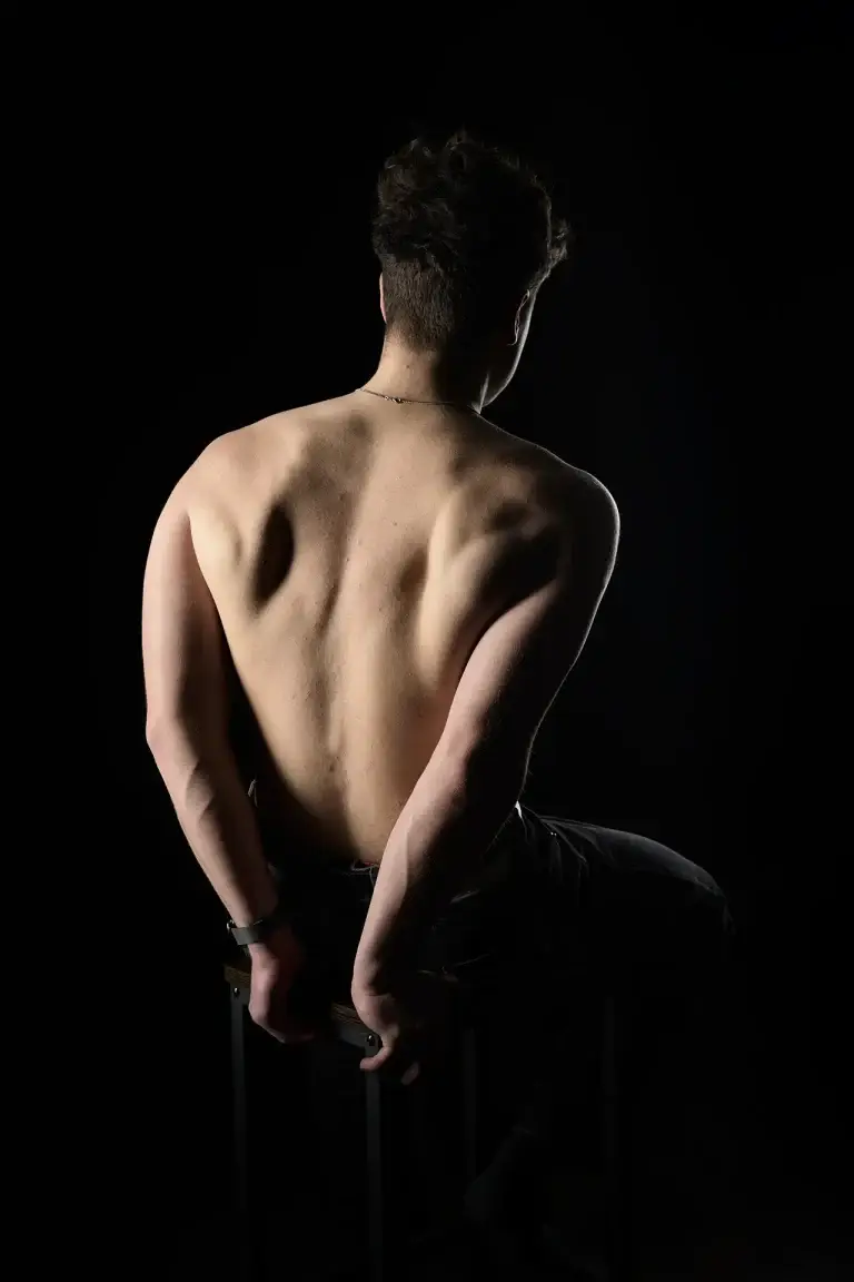 Portrait fitness de dos sur fond noir, mains derrière le dos