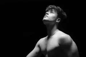 Portrait noir et blanc d'une jeune homme torse nu. Plan épaule et lumière en douche mettant en valeur sa musculature.