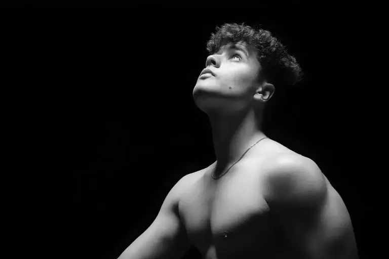 Portrait noir et blanc d'une jeune homme torse nu. Plan épaule et lumière en douche mettant en valeur sa musculature.