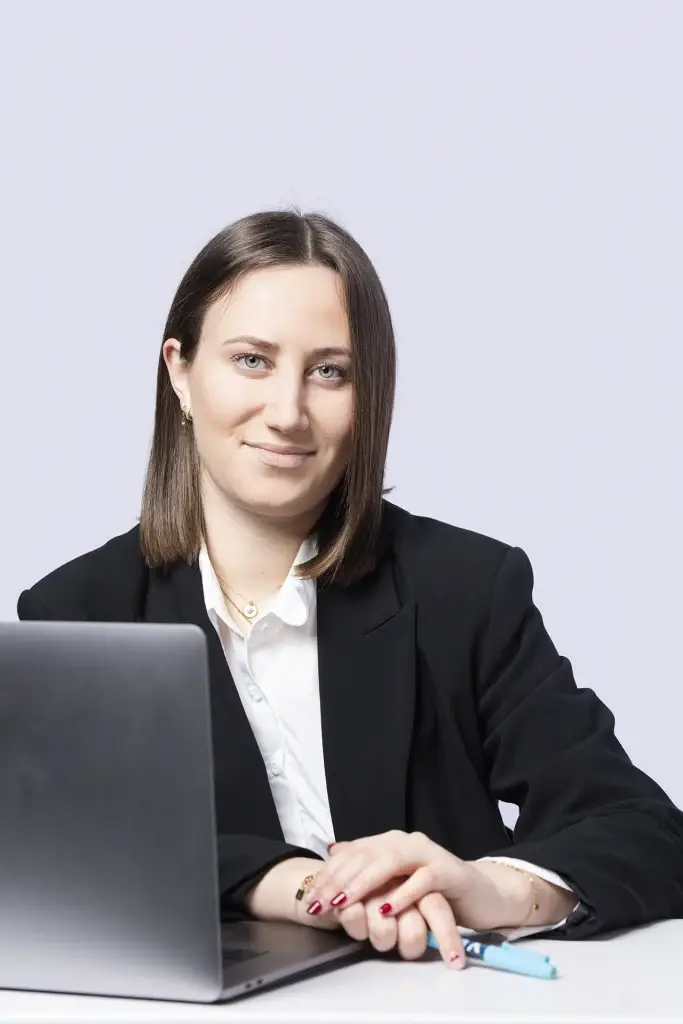 Portrait professionnel d'une jeune femme sur Tarbes. Celle-ci est assise devant son ordinateur portable et elle est souriante.