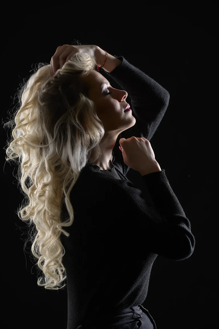 shooting beauté à Tarbes pour une jeune femme blonde. Lumière en clair obscur. La modele ferme les yeux. Lumière douce et rasante, photo en couleur.