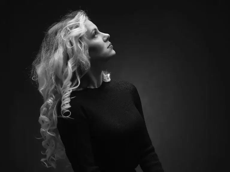 Portrait en contre jour et en noir et blanc d'une jeune femme blonde. Plan taille et lumière douce pour mettre en valeur sa beauté.