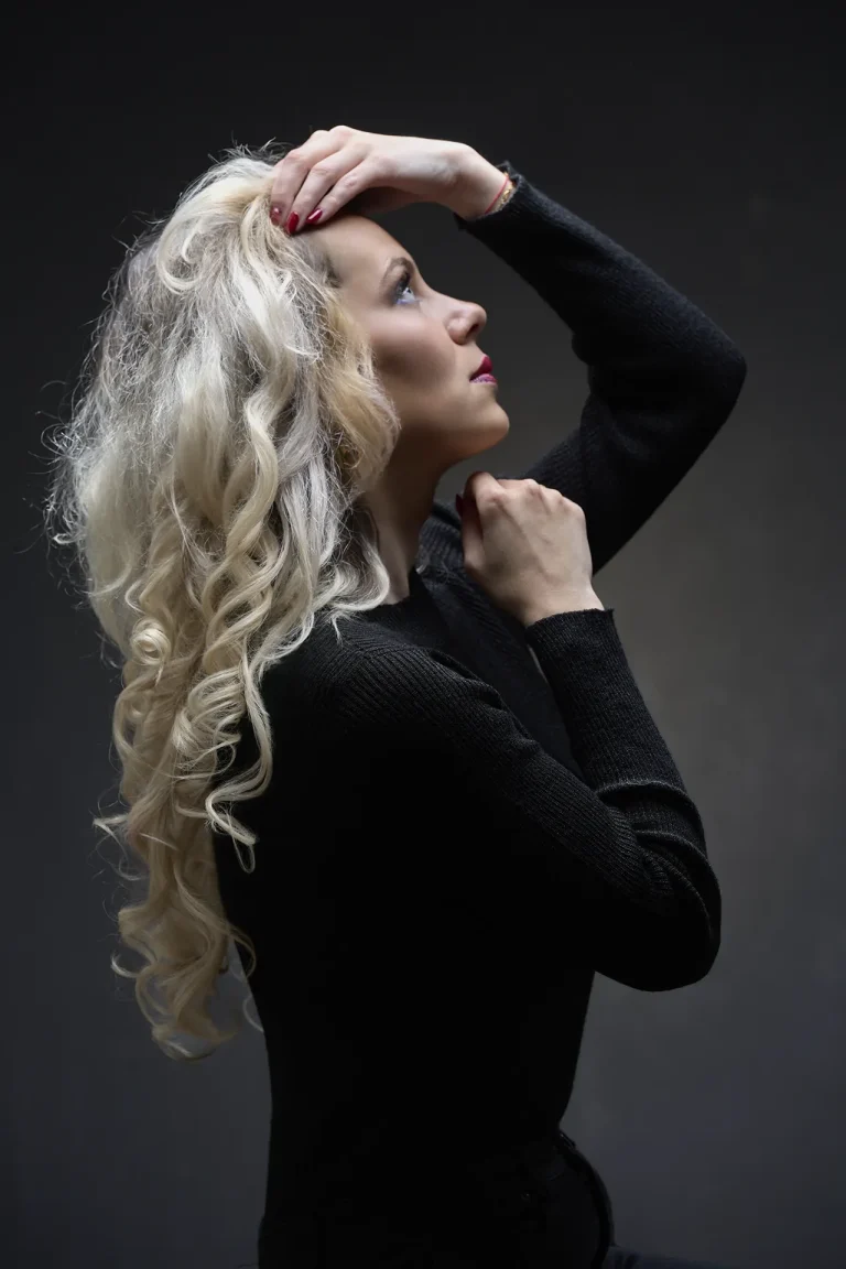 Book modèle en clair-obscur, jeune femme blonde sur fond noir, lumière en douche