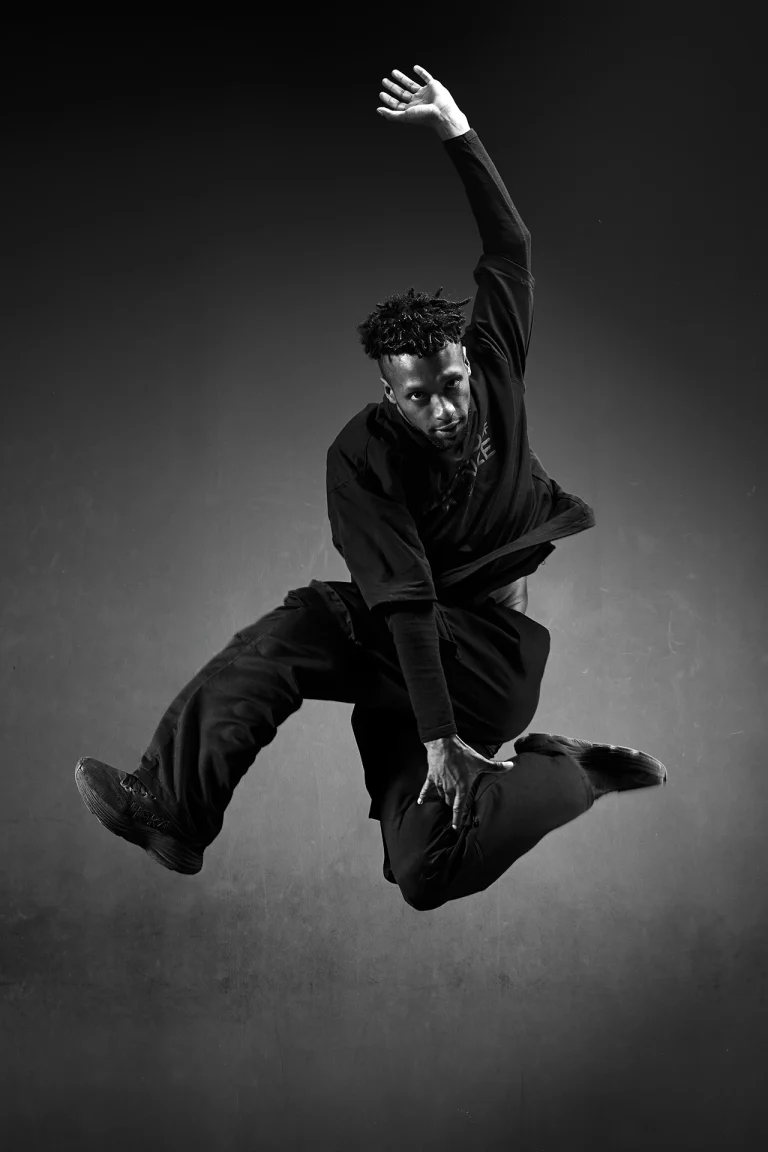 Danseur électro en plein saut, bras levé, noir et blanc
