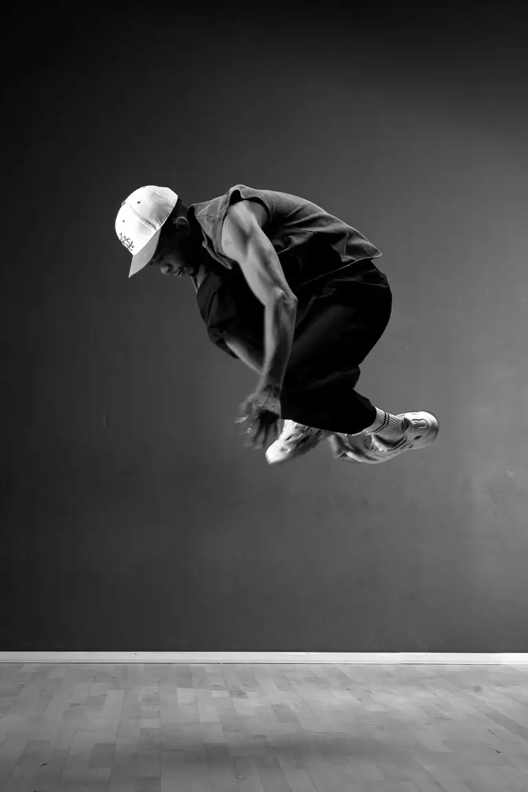 Danseur hip-hop à la casquette en plein saut, noir et blanc