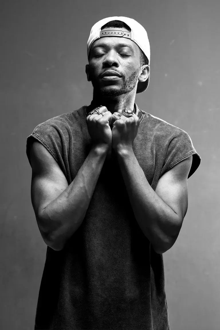Danseur hip-hop à la casquette, poings serrés sous le menton, noir et blanc
