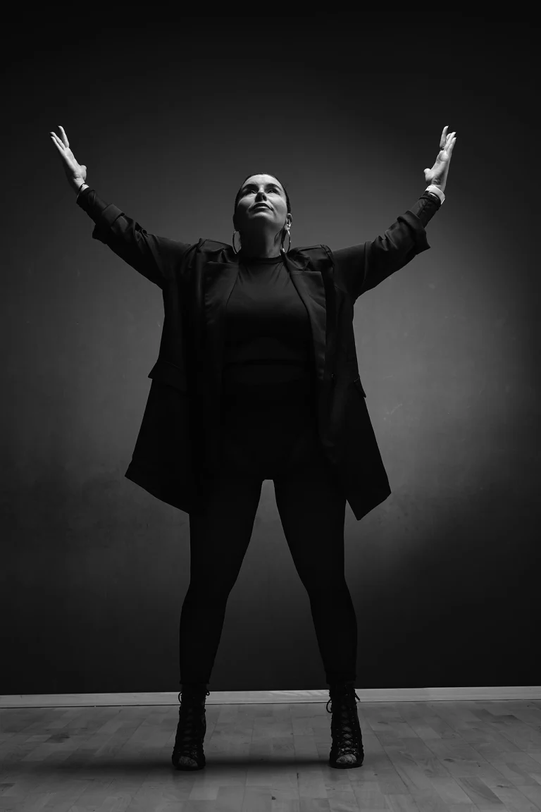 Danseuse, bras ouverts vers le haut, lumière en douche, noir et blanc