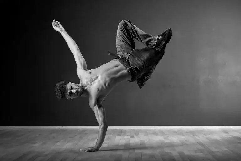 Portrait de Zaid, un danseur de Hip Hop professionnel en appuis sur un seul bras. La lumière en douche révèle toute la beauté du mouvement et l'attitude générale du danseur.