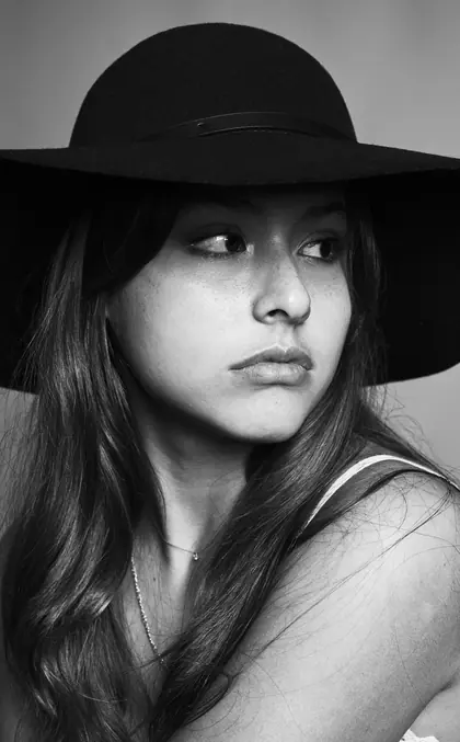 Portrait en noir et blanc d’une jeune femme au chapeau noir