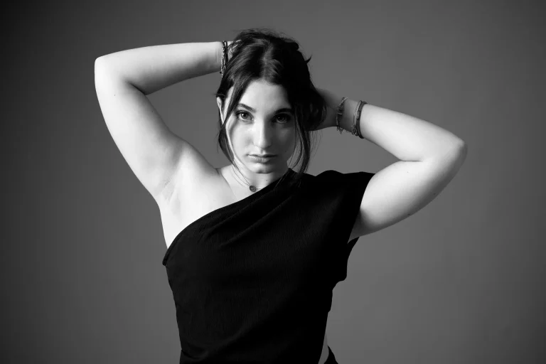 Book modèle en noir et blanc, bras levés derrière la tête