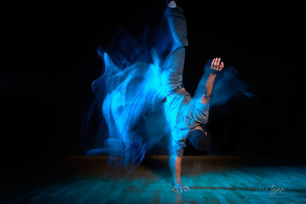 Danseur en appui sur une main, traînées de lumière bleue