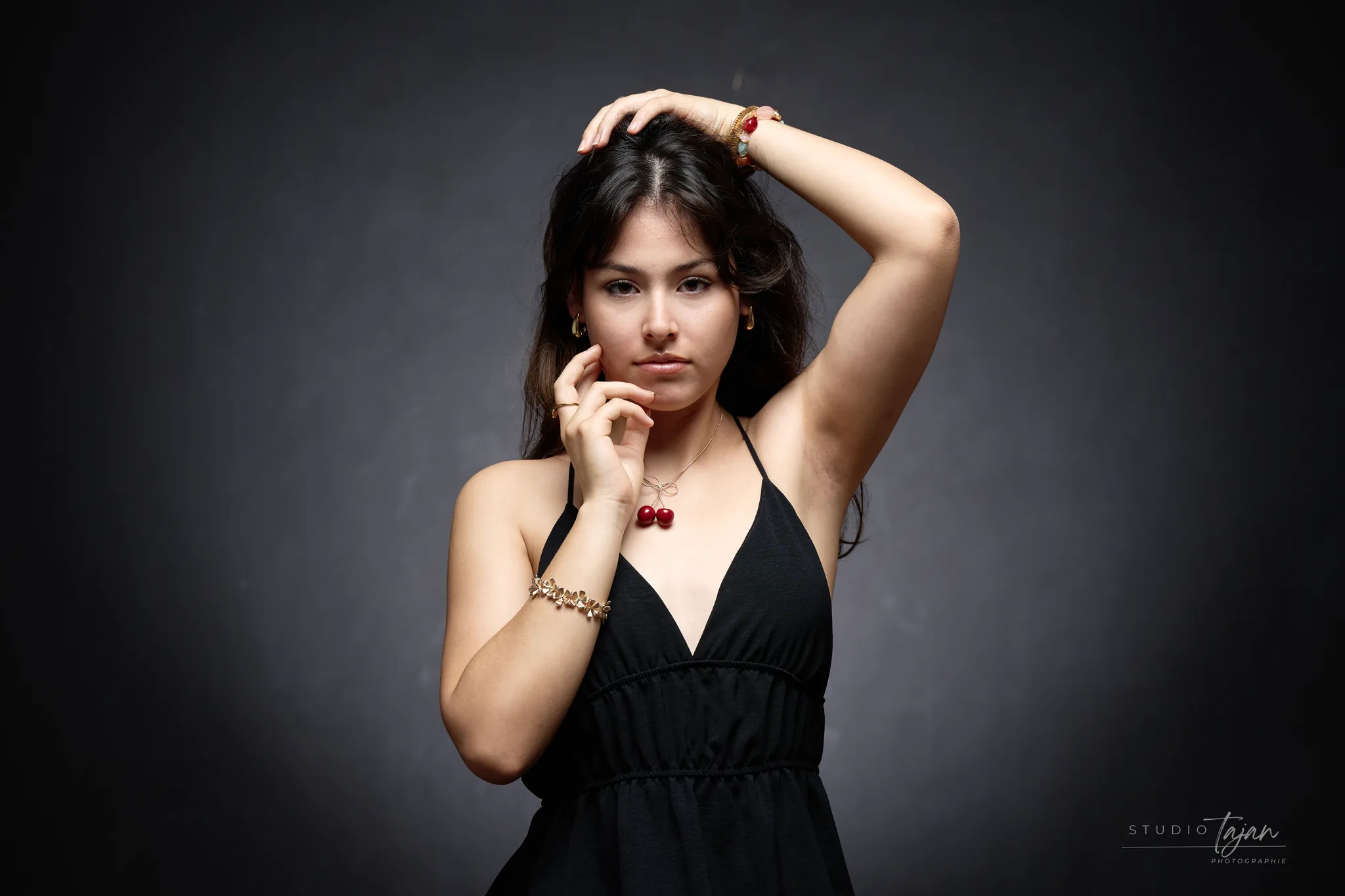 Portrait féminin en couleur, pendentif rouge sur robe noire, fond sombre