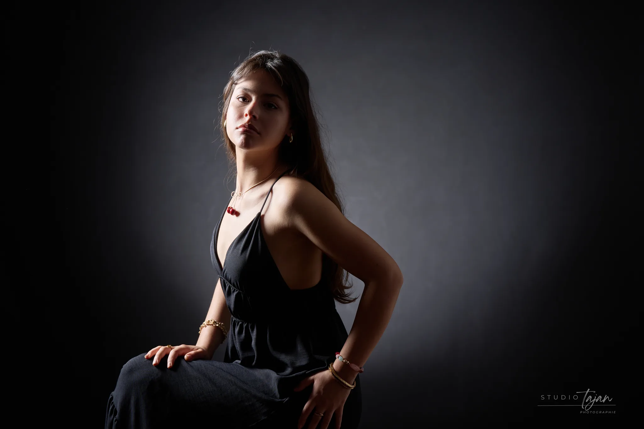 Portrait féminin assis de trois quarts, en couleur, dans la pénombre