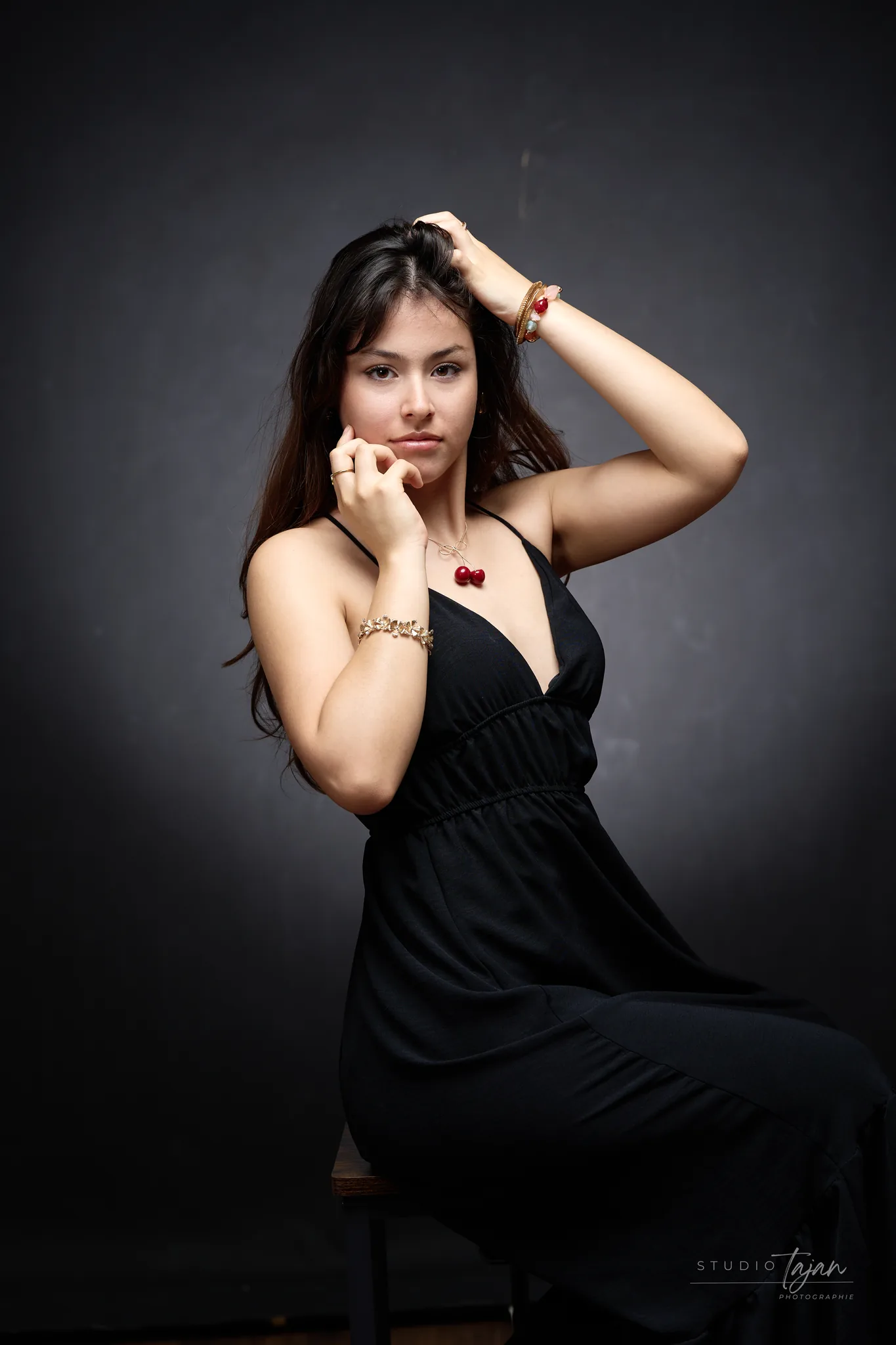 Portrait féminin assis en couleur, robe noire, fond sombre