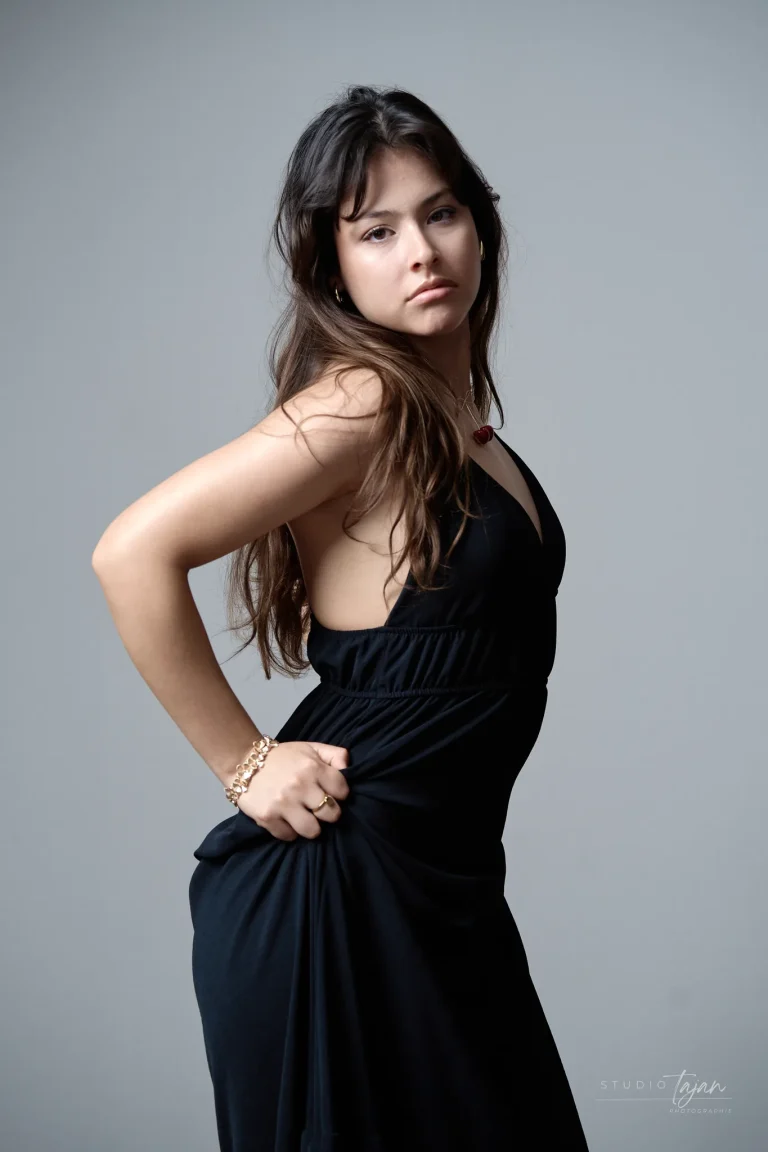 Portrait féminin en couleur sur fond gris clair, de profil, regard vers l’objectif