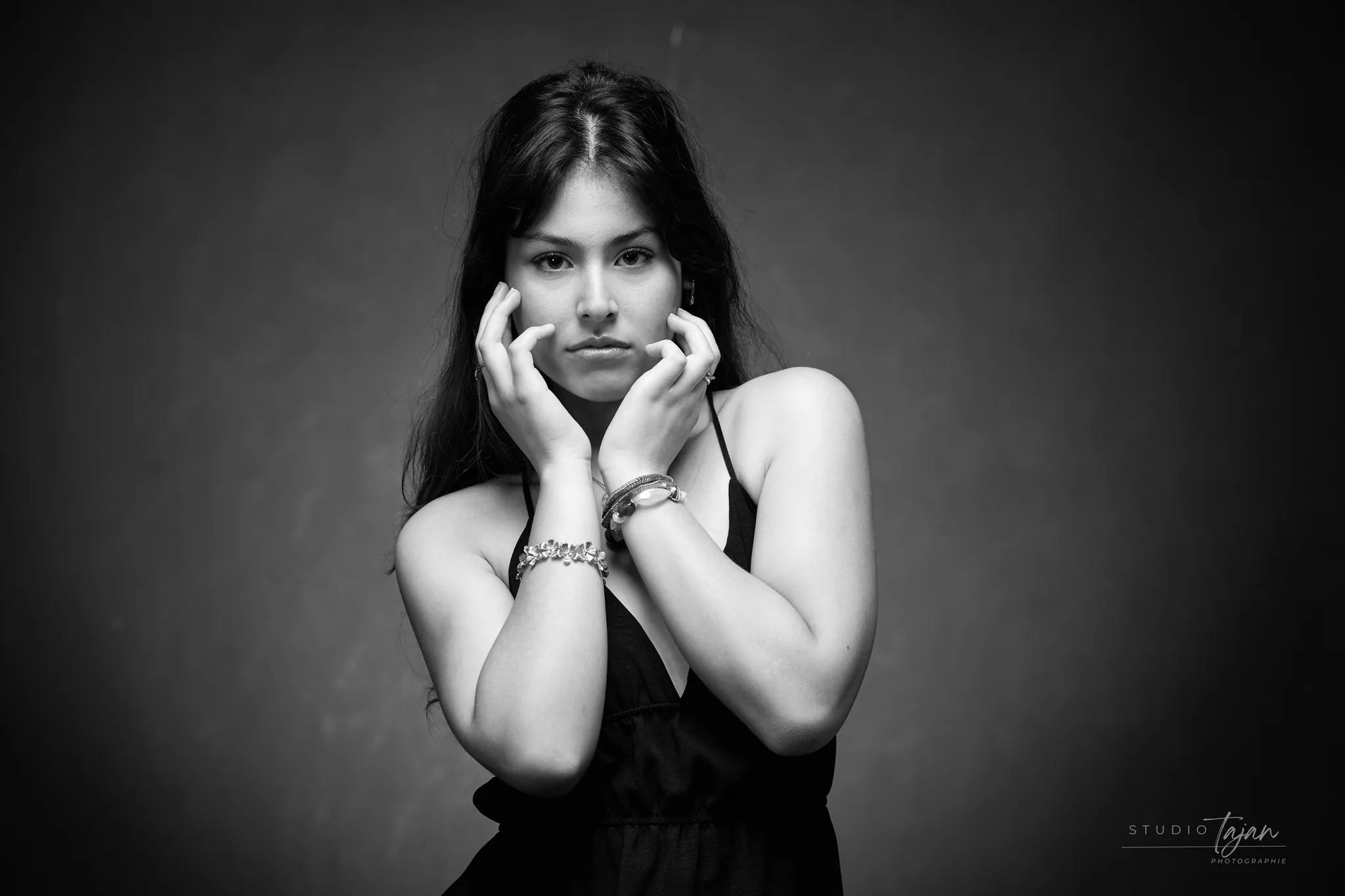 Portrait féminin en noir et blanc, mains jointes contre le visage