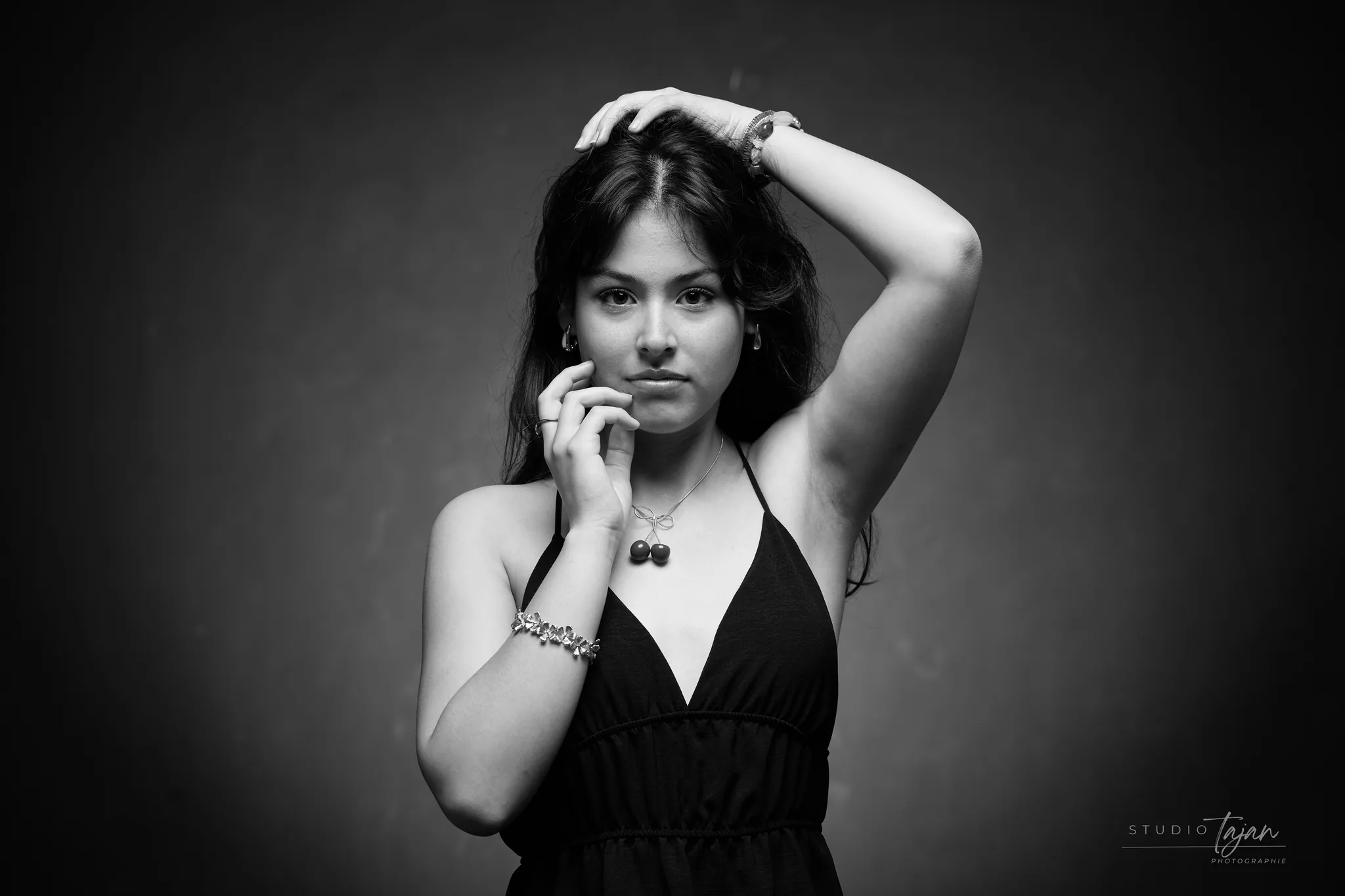 Portrait féminin en noir et blanc, bras levés, regard direct
