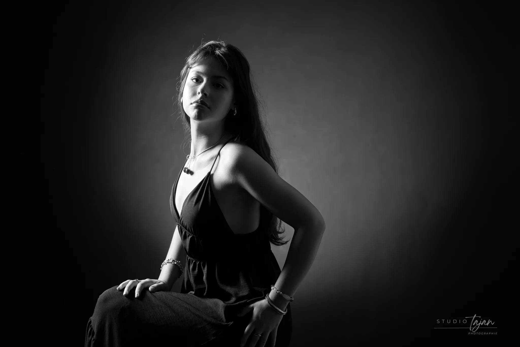 Portrait féminin assis de trois quarts, en noir et blanc